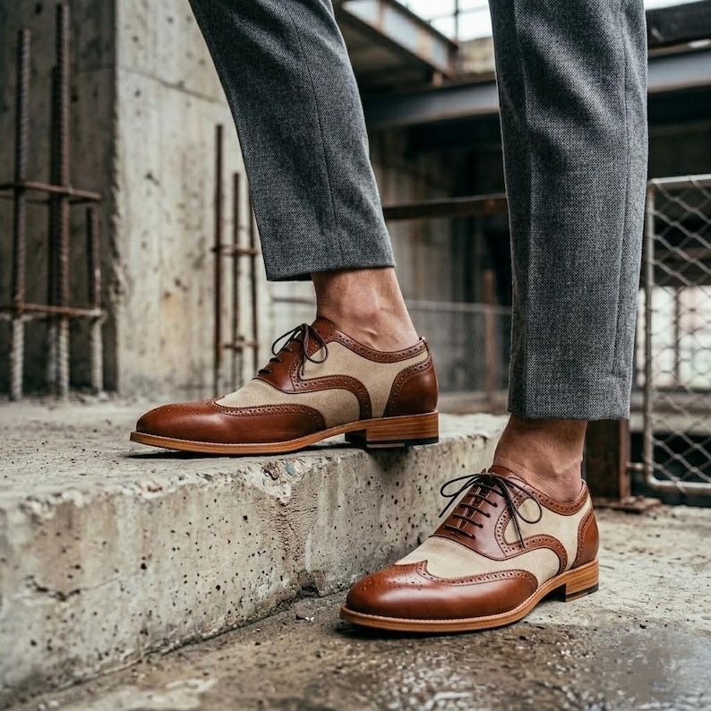 Man wearing vintage-style spectator brogues with charcoal grey trousers standing on stone steps.