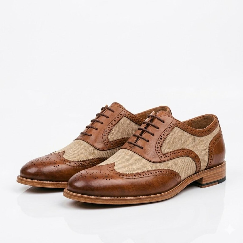 Professional shot of brown leather and canvas oxford shoes on a white reflective surface.