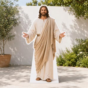 Peut inclure: Une silhouette en carton grandeur nature représentant un homme aux longs cheveux bruns et à la barbe, vêtu d'une tunique crème et d'un châle beige drapé. La figure se tient les bras tendus, paumes vers l'avant, et porte des sandales marron.
