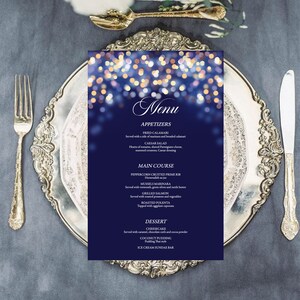 Peut inclure: Un menu bleu avec un fond blanc et des paillettes dorées. Le menu liste des apéritifs, des plats principaux et des desserts. Les plats proposés incluent des calamars frits, une salade César, une côte de bœuf en croûte de poivre, des moules à la marinara, du saumon grillé, de la polenta rôtie, un cheesecake, un pudding à la noix de coco et un bar à sundae glacé.