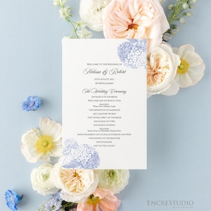 Pode incluir: Um cartão de programa de casamento retangular branco com ilustrações florais azuis nos cantos superior e inferior. O texto diz: Welcome to the wedding of Melissa & Robert, 25th August 2027, Rivervale Barn, e lista a cerimônia.