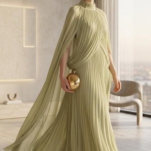 Puede incluir: Un vestido largo plisado de color verde oliva claro con cuello alto, detalles de botones y una capa integrada que cae sobre los hombros. La prenda se combina con un peque&ntilde;o bolso de mano redondo de metal dorado pulido.