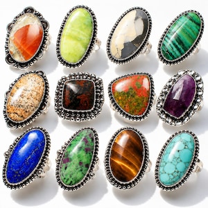 Peut inclure: Une collection de douze bagues ornées de diverses pierres précieuses polies serties dans des montures en métal argenté. Les pierres incluent des tons orange, vert lime, crème et noir, vert rayé, beige tacheté, brun foncé, rouge et vert, violet, bleu, vert et rose, œil-de-tigre brun et turquoise.