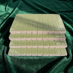 Nail buffer blocks bulk set stacked in four layers wrapped in plastic featuring green and pink double-sided mini nail file buffers for nail care manicure salon use displayed on green velvet background