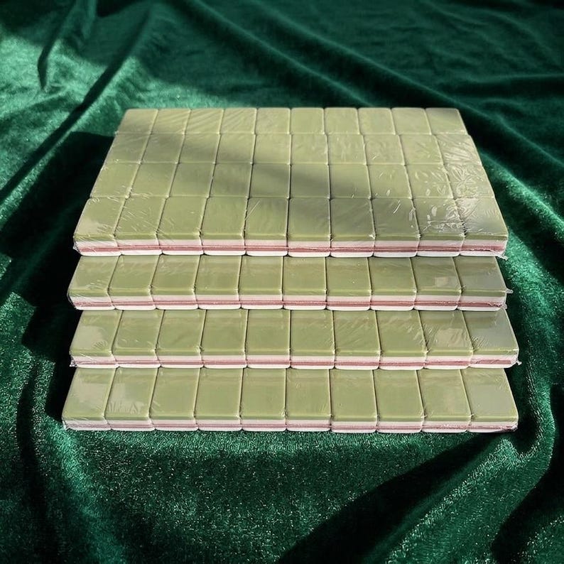 Nail buffer blocks bulk set stacked in four layers wrapped in plastic featuring green and pink double-sided mini nail file buffers for nail care manicure salon use displayed on green velvet background