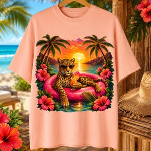 Pode incluir: Uma t-shirt cor de pêssego com uma estampa gráfica de um leopardo usando óculos de sol, relaxando em uma boia rosa brilhante no oceano. A cena inclui palmeiras, um pôr do sol e flores de hibisco vermelhas vibrantes ao redor do leopardo.