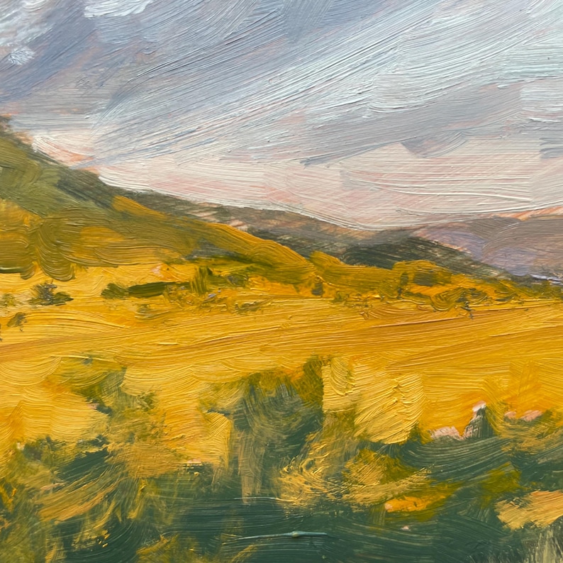 Golden autumn grasses of the high plains near Miami, New Mexico, glow beneath the first light of day in October Morning Along Miami Lane, an original oil painting by Santa Fe artist Dawn Chandler. Rolling slopes lead west toward the distant Sangre de Cristo Mountains of Philmont, bathed in soft sunrise warmth.