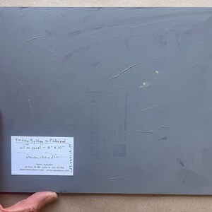 Back of original New Mexico landscape oil painting “Finding My Way to Pedernal” by Santa Fe artist Dawn Chandler, showing the gray-painted 8 x 10 inch panel held at the lower left by the artist’s hand, with a white signed label identifying the title, medium, size and Dawn Chandler’s Santa Fe contact information, confirming this is a one-of-a-kind artwork.