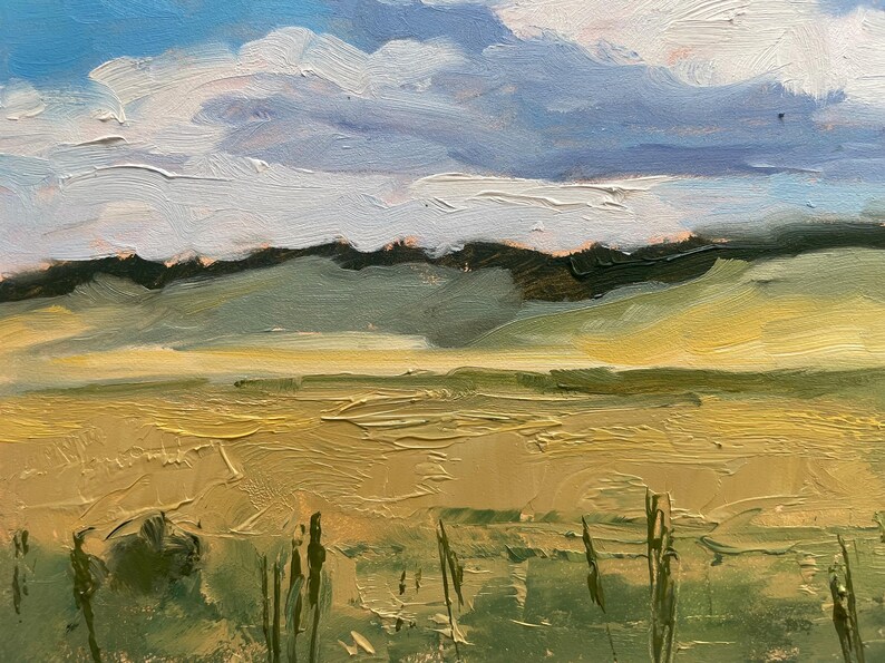 Close‑up detail of original New Mexico landscape oil painting Under a High Country August Sky by Santa Fe artist Dawn Chandler, focusing on the foreground meadow with textured impasto strokes of ochre and olive greens, delicate vertical grasses, and distant soft green hills beneath bands of pale clouds and blue sky, emphasizing the tactile surface of the oil on panel.