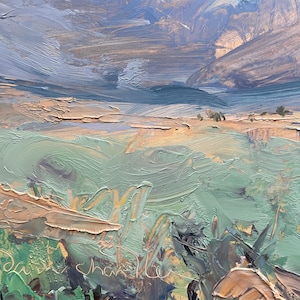 Close-up detail of original New Mexico landscape painting Spring Morning Over the Taos Mountains by Santa Fe artist Dawn Chandler, focusing on the richly textured foreground where thick impasto strokes describe mint and sage green spring grasses, ochre earth, and hints of distant fields beneath shadowed blue foothills, revealing the physical brush marks, palette-knife ridges, and the artist’s signature inscribed into the wet paint.