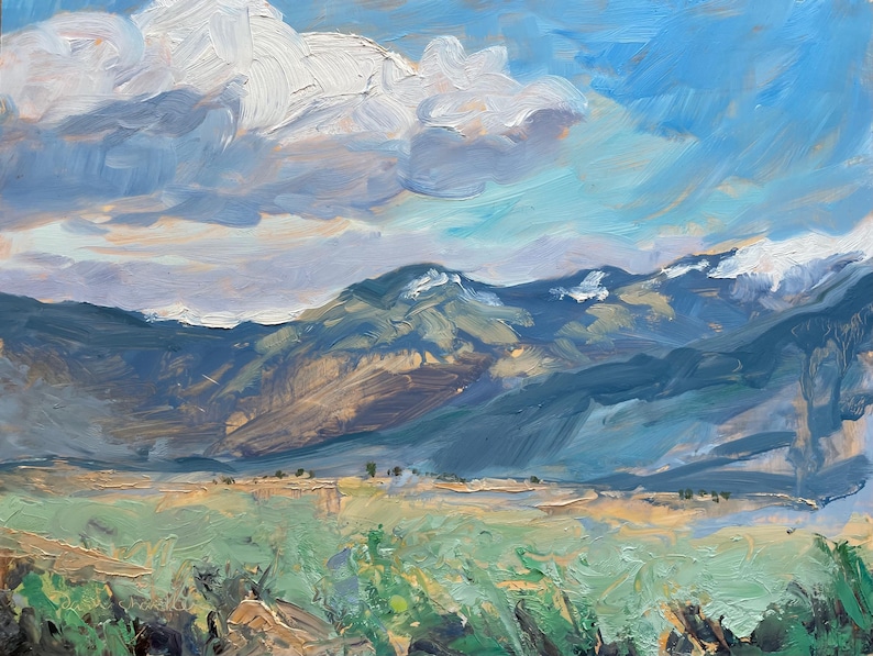 Original New Mexico landscape oil painting Spring Morning Over the Taos Mountains by Santa Fe artist Dawn Chandler, showing a wide Taos valley with thick palette-knife foreground grasses, soft turquoise and sage greens, distant blue-violet mountains with lingering snow, and a vast, expressive sky of sweeping clouds and light-filled blue brushstrokes, capturing the freshness and energy of a high desert spring morning.