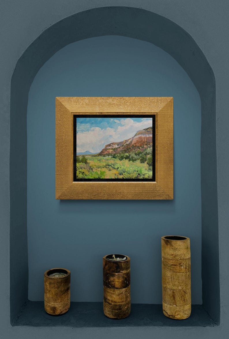 Original New Mexico landscape oil painting “Finding My Way to Pedernal” by Santa Fe artist Dawn Chandler, framed in a textured gold frame and displayed in a blue arched niche with three rustic wooden candleholders below, demonstrating how this luminous Abiquiu mesa and Pedernal view becomes a focal point in Southwestern or contemporary decor.