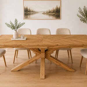 May include: A rectangular wooden dining table with a herringbone pattern top and a central cross-leg base, surrounded by six upholstered chairs with light beige fabric and tapered wooden legs, featuring a white tray with a vase and candle.