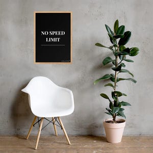 May include: A rectangular wall art print in a light wood frame featuring a black background with the white text NO SPEED LIMIT and a horizontal line underneath. The print is displayed above a white molded plastic chair with wooden legs.