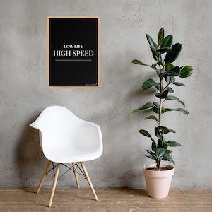 May include: A rectangular wall art print in a light wood frame featuring a black background with the white text LOW LIFE HIGH SPEED and a horizontal line. Below the text is the small white logo FUEL & STYLE.