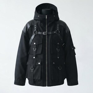 K&ouml;nnte beinhalten: Eine schwarze Kapuzenjacke mit Frontrei&szlig;verschluss, mehreren Utility-Taschen mit silberfarbenen Druckkn&ouml;pfen und einem integrierten Gurtsystem mit verstellbaren Riemen, Metallringen und Nieten &uuml;ber Brust und Schultern.