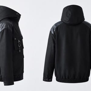 K&ouml;nnte beinhalten: Eine schwarze Kapuzenjacke in Vorder- und R&uuml;ckansicht. Die Jacke verf&uuml;gt &uuml;ber eine Kapuze, lange &Auml;rmel mit B&uuml;ndchen, einen gerippten Saum sowie mehrere Utility-Taschen mit Riemen und Metallbeschl&auml;gen an der Vorderseite und am &Auml;rmel.