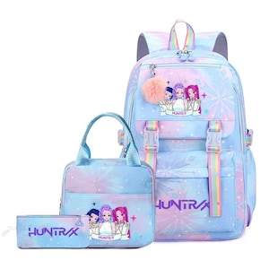 May include: A three-piece bag set featuring a backpack, a lunch bag, and a pencil case in a pastel blue and purple gradient with star and snowflake patterns. Each item displays the text HUNTR/X and a graphic of three anime-style characters.