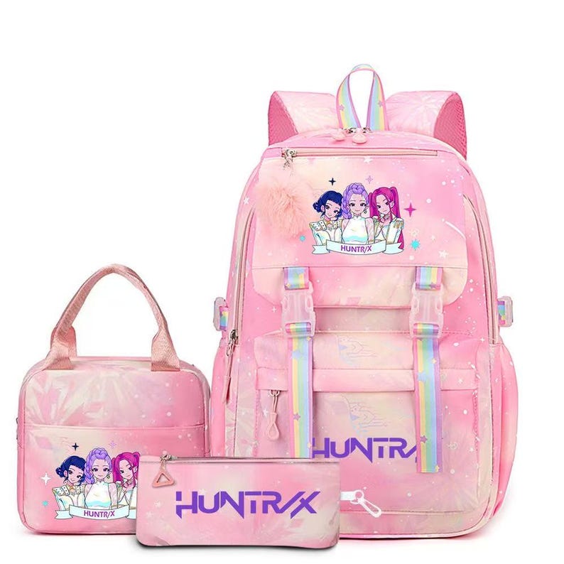 May include: A pink backpack, lunch bag, and pencil case set featuring a repeating anime-style graphic of three characters and the text HUNTR/X. The items have rainbow-striped straps, pink zippers, and a fluffy pink pom-pom attached to the backpack.