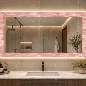 May include: A rectangular wall mirror featuring a wide, polished pink stone frame with a natural crystalline texture. The mirror includes integrated LED backlighting that emits a soft glow around the perimeter, illuminating the reflective surface.