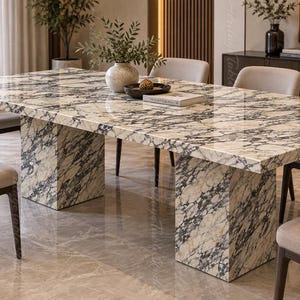 May include: A rectangular dining table featuring a polished cream and black marble surface with matching block-style pedestal legs, surrounded by six upholstered chairs with dark wooden legs and light beige fabric seats.