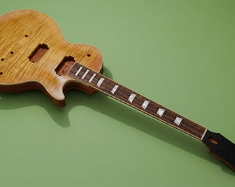 May include: An unfinished electric guitar body and neck with a light brown flamed maple top. The dark wood fretboard features rectangular pearloid inlays. The headstock is solid black, and the body includes routed cavities for pickups and controls.