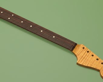 May include: A guitar neck featuring a light-colored, flamed maple headstock with six tuner holes and a dark brown fretboard. The fretboard is inlaid with small, circular white position markers along the length of the neck for navigation.
