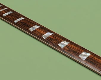 May include: A long, rectangular guitar fretboard made of dark brown wood with a prominent grain pattern. It features multiple silver metal frets and inlaid trapezoidal markers made of iridescent, pearlescent material positioned along the surface.