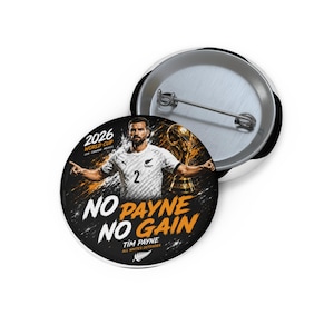 Puede incluir: Un botón redondo con alfiler que muestra una imagen del futbolista Tim Payne con camiseta blanca. El texto dice 2026 WORLD CUP, NO PAYNE NO GAIN, TIM PAYNE y ALL WHITES DEFENDER. El fondo es negro con detalles en naranja y un trofeo dorado.