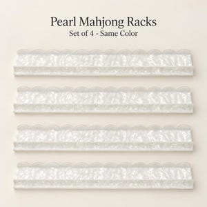 May include: A set of four white pearl-finish Mahjong racks, each featuring a scalloped top edge and a textured, marbled appearance. The text Pearl Mahjong Racks and Set of 4 - Same Colour is printed above the four identical horizontal racks.