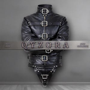 May include: A black leather garment featuring a high collar, long sleeves, and multiple horizontal straps with silver-toned metal buckles and rivets. The front includes a central zipper closure. The text QYZORA EST. 2024 ETSY EXCLUSIVE is visible.