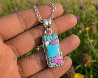 May include: A rectangular pendant necklace featuring a mosaic of turquoise and pink stones set in a silver frame with a rope-textured border. The pendant hangs from a silver chain link necklace. The stone inlay displays a mix of bright blue, white, and magenta segments.