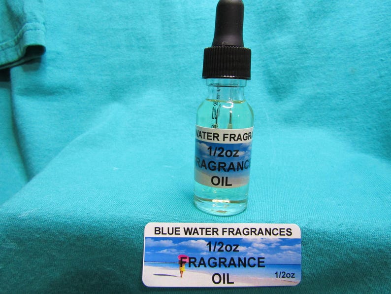 a bottle of water fragrance oil and a label for blue water fragrances, both placed on a blue fabric background.