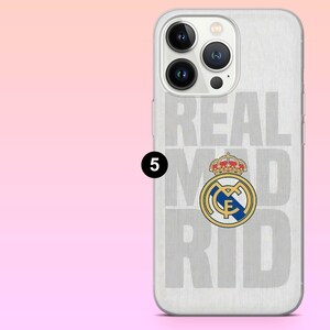 May include: A clear smartphone case featuring a brushed silver metallic background with the text REAL MADRID in large light gray letters and the official Real Madrid football club crest in blue, gold, and red colors centered on the back.