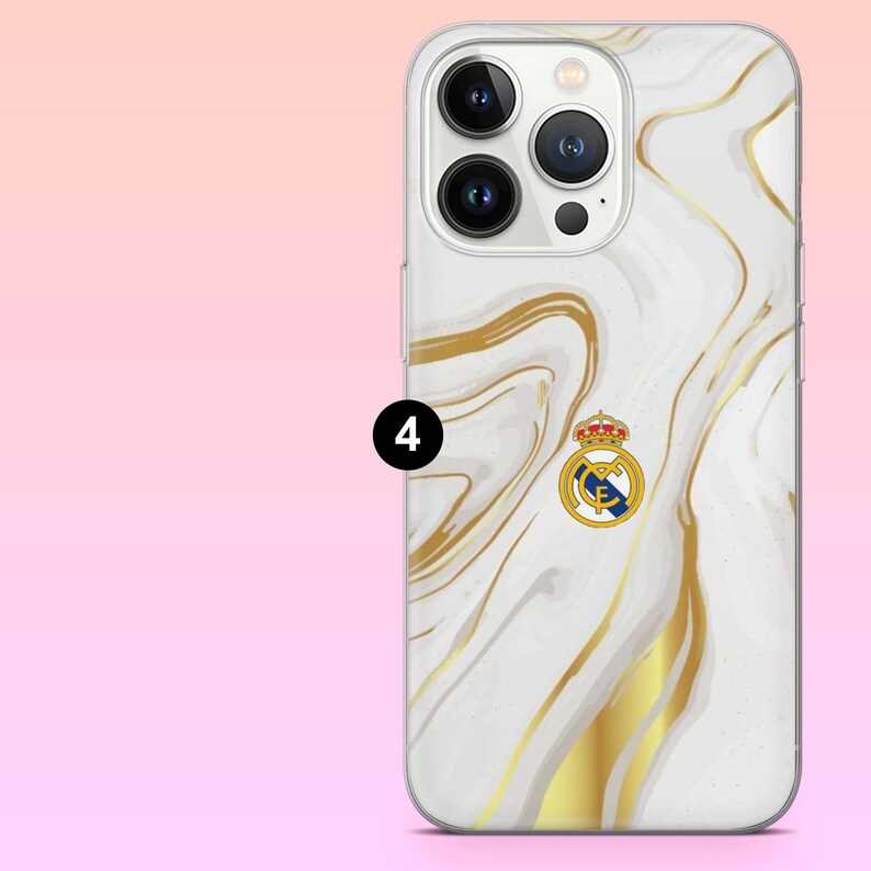 May include: A smartphone case featuring a white and gold marble pattern with a Real Madrid football club logo centered on the back. The case has a cutout for the triple camera system and flash. A black circle with the number 4 is visible.