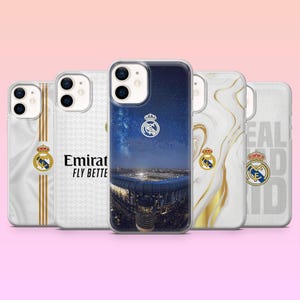 May include: Five smartphone cases featuring Real Madrid branding. Designs include a stadium night view, white fabric textures with gold stripes, the Emirates Fly Better logo, gold marble swirls, and the Real Madrid text with the club crest.
