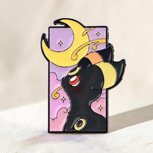 May include: A rectangular enamel pin featuring a black creature with yellow markings and red eyes. The background is a light purple sky with pink clouds and a large yellow crescent moon. The design includes small yellow stars and black outlines.