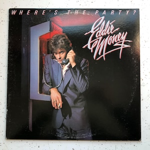 May include: A black vinyl record album cover featuring a man in a blue suit talking on a red payphone. The album title is "Where's The Party?" and the artist is "Eddie Money".