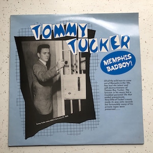 May include: A blue and white record album cover with a photo of a man in a suit. The album cover has the text "Tommy Tucker Memphis Badboy!" and a description of the musician.