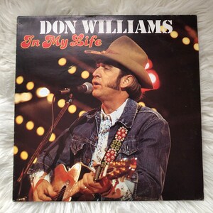 May include: Vintage vinyl record album cover for Don Williams' "In My Life." The cover features a photo of Williams singing and playing a guitar, wearing a cowboy hat and denim jacket. The background is dark with stage lights.