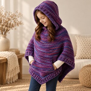 Peut inclure: Un poncho à capuche tricoté dans un fil multicolore aux nuances de violet, bleu et rose. Le vêtement présente une bordure en tricot côtelé le long de la capuche, de l'ourlet et des ouvertures de manches, ainsi qu'une grande poche kangourou.