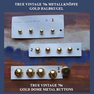Può includere: Una collezione di bottoni in metallo dorato vintage a forma di semisfera, disposti su tre cartoncini bianchi numerati 1, 2 e 3. I bottoni presentano una finitura liscia e riflettente e sono presentati in diverse dimensioni.