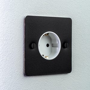 May include: A square electrical wall socket featuring a textured matte black faceplate with rounded corners. The centre of the socket is white with two circular black screws positioned on the left and right sides to secure the cover plate to the wall.