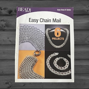 May include: A softcover instructional book titled Easy Chain Mail from the Bead & Button Easy-Does-It Series. The cover features four photographs of silver chain mail jewelry projects, including necklaces and bracelets, with the text 6 PROJECTS.