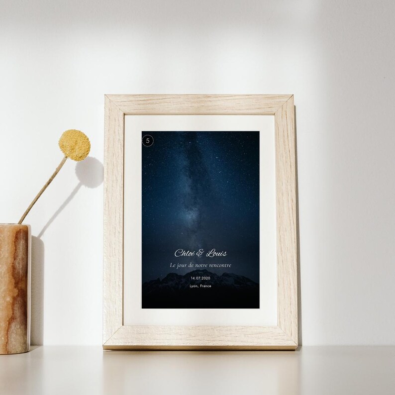 K&ouml;nnte beinhalten: Ein gerahmter Druck mit einem dunkelblauen Nachthimmel und einer sternenklaren Galaxie &uuml;ber einer Bergsilhouette. Der Text lautet Chlo&eacute; & Louis, Le jour de notre rencontre, 14.07.2020, Lyon, France, mit einem kleinen Kreis, der die Zahl 5 enth&auml;lt.