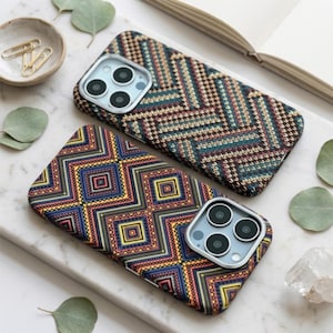 Può includere: Due cover rettangolari per smartphone con motivi distinti. Una cover presenta una complessa trama a maglia con motivo a spina di pesce in tonalità marrone, verde acqua e nero. L'altra mostra un motivo geometrico a rombi in blu, giallo e arancione.