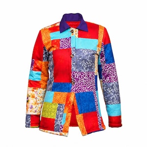 May include: A long-sleeve button-up jacket featuring a vibrant patchwork design with various fabric squares in red, blue, orange, purple, and yellow. The garment includes a solid purple collar and a front button closure with three visible buttons.