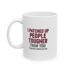 May include: A white ceramic mug with a handle featuring the dark red text I PATCHED UP PEOPLE TOUGHER THAN YOU and the grey text I TAKE MY COFFEE BLACK printed on the front. The mug has a smooth, cylindrical body and a standard curved handle.