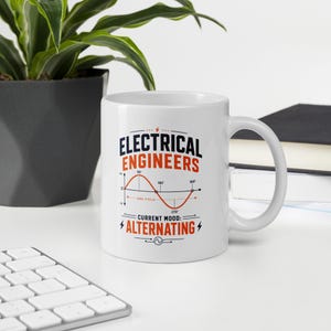 Peut inclure: Un mug en céramique blanc avec un motif graphique portant le texte ELECTRICAL ENGINEERS et CURRENT MOOD: ALTERNATING en noir et orange. Le design comprend un diagramme d'onde sinusoïdale rouge représentant un cycle avec des degrés de 90 à 360.