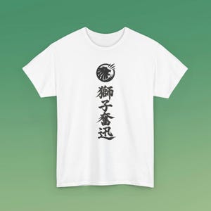 May include: A white short-sleeve t-shirt featuring a black graphic centered on the chest. The graphic consists of a circular lion head icon positioned above four vertical Japanese kanji characters that read 獅子奮迅 in black ink.